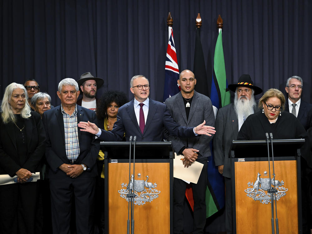 Australian Prime Minister Anthony Albanese, at the left podium, is surrounded by members of the First Nations Referendum Working Group as he speaks during a press conference at Parliament House in Canberra, Thursday, March 23, 2023.