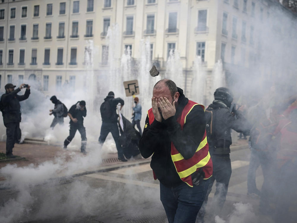 Protesters run amid the tear gas during a demonstration in Lyon, central France, Thursday, March 23, 2023. French unions are holding their first mass demonstrations Thursday since President Emmanuel Macron enflamed public anger by forcing a higher retirement age through parliament without a vote.