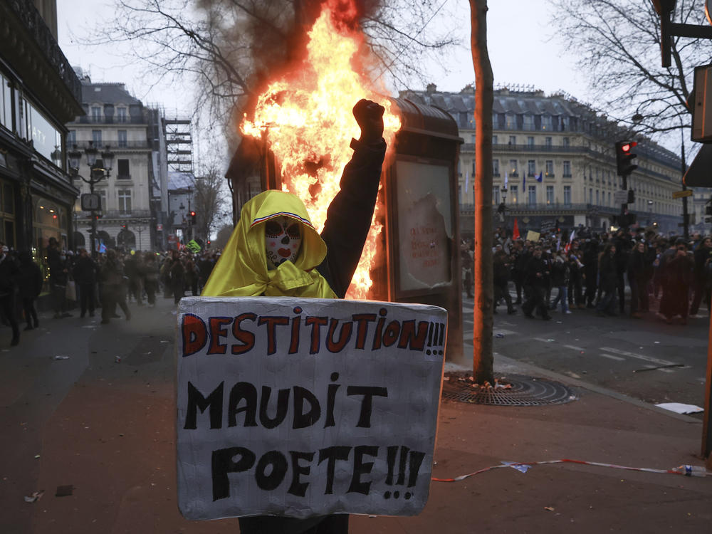 A protester holds a placard that reads, 