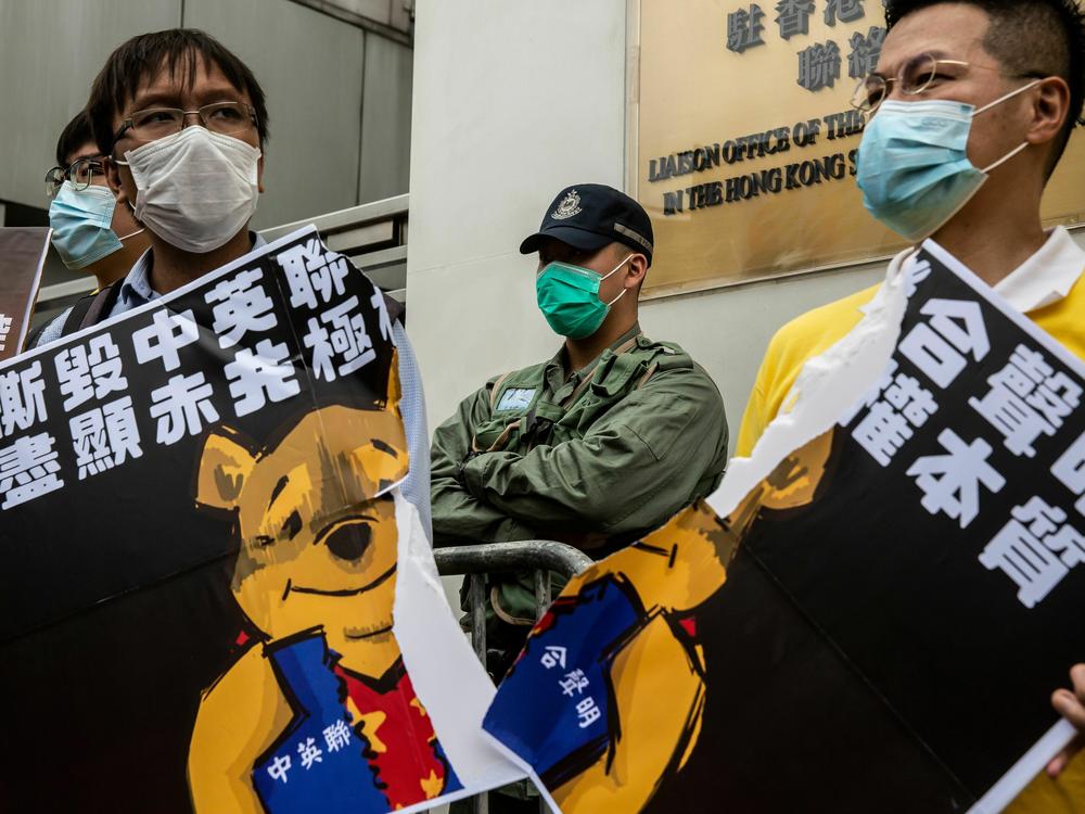 Pro-democracy activists tear a placard of Winnie-the-pooh that represents Chinese President Xi Jinping during a protest against a proposed new security law outside the Chinese Liaison Office in Hong Kong on May 24, 2020.