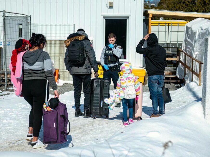 An officer speaks to migrants as they arrive at the Roxham Road border crossing in Quebec, Canada, earlier this month.