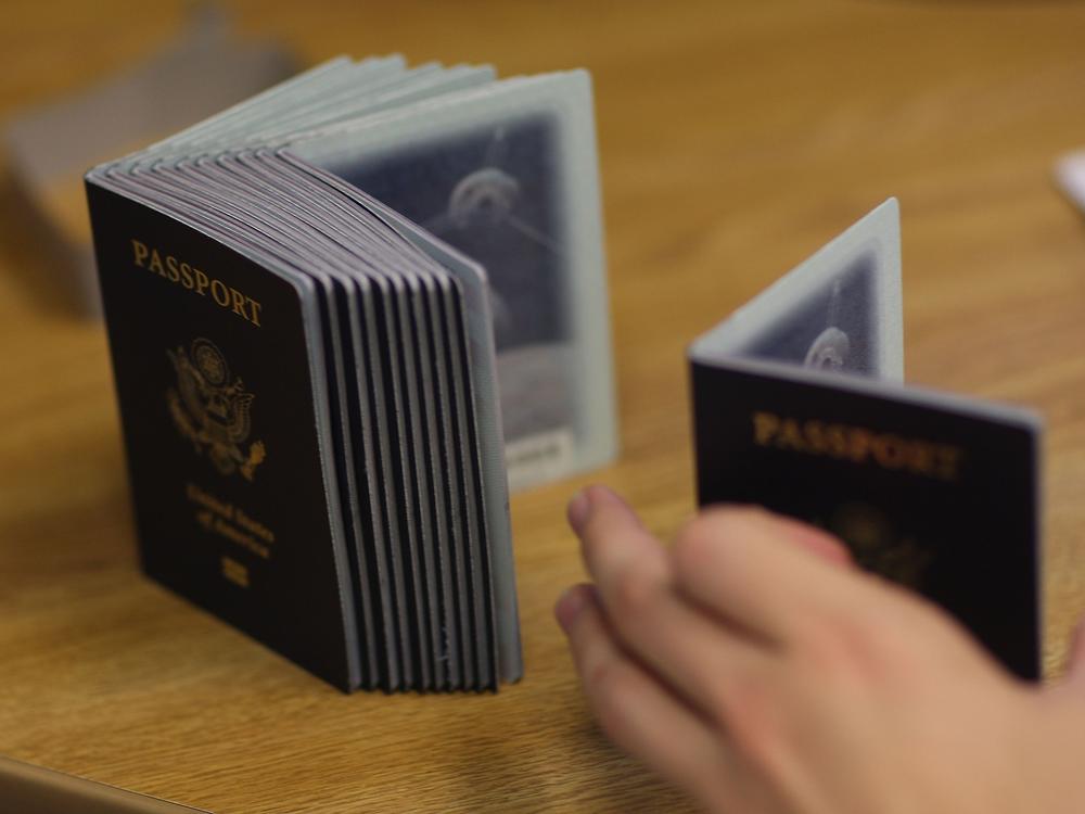 A Passport Processing employee uses a stack of blank passports to print a new one at the Miami Passport Agency June 22, 2007 in Miami, Fla. Passport processing times are high due to increased demand.