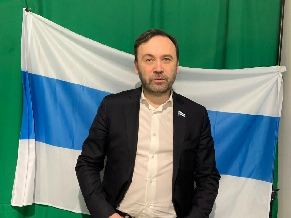Ilya Ponomarev is the founder of February Morning, an opposition Russian-language online newscast aimed at viewers in Russia. Behind him is a flag symbolizing the 