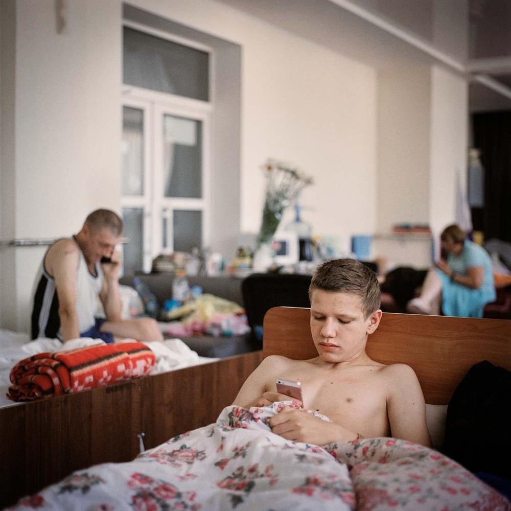 A boy lying in bed at a shelter that provides more permanent accommodation for internally displaced people at a factory owned by the Ukrainian Association for the Blind in Dnipro city, June 2022.
