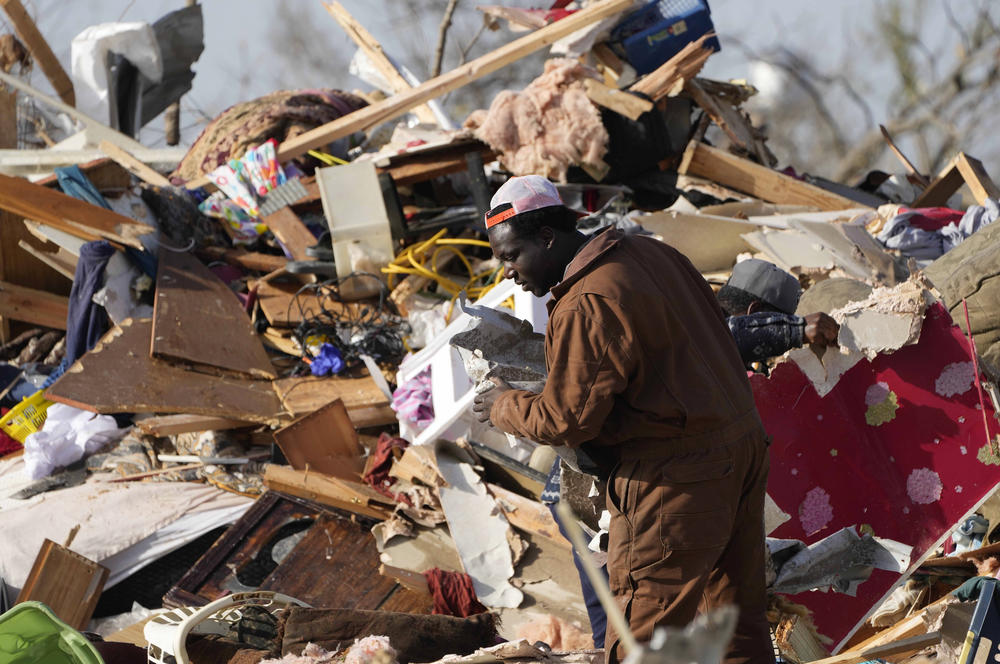 A resident looks through the piles of debris, insulation, and home furnishings to see if anything is salvageable at a tornado-demolished mobile home park in Rolling Fork, Miss.