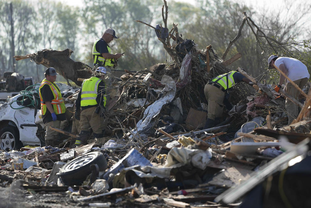 Emergency rescuers and first responders climb through a tornado demolished mobile home park looking for bodies that might be buried in the piles of debris, insulation, and home furnishings in Rolling Fork, Miss.