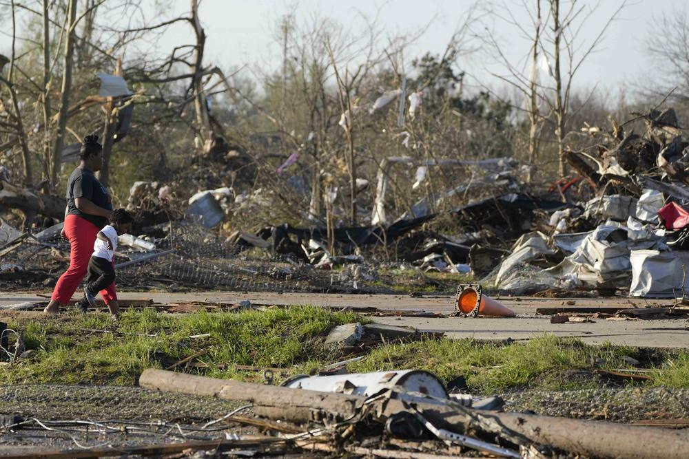 A pair of residents walk through the remains of their demolished mobile home park, looking through the piles of debris, insulation, and home furnishings to see if anything is salvageable in Rolling Fork, Miss.