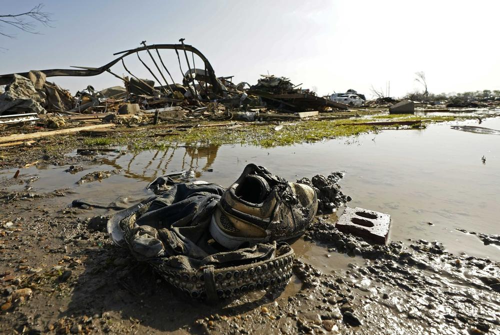 A pair of sneakers and pants lay in front of the skeletal remains of the underside of a mobile home in Rolling Fork, Miss.