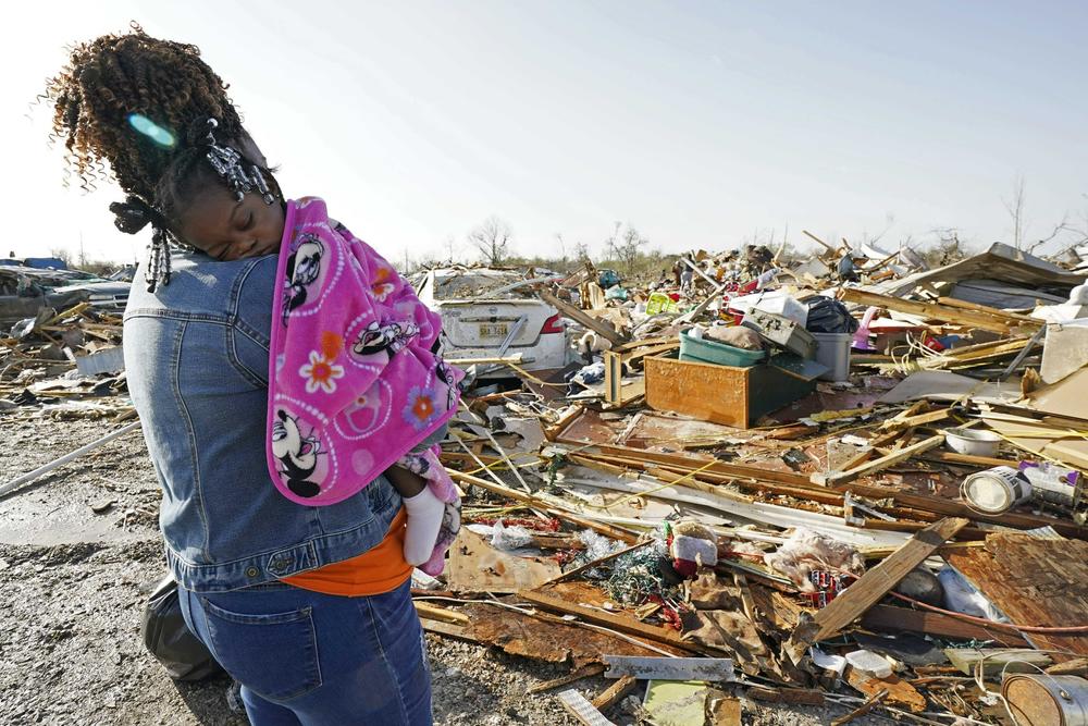 Wonder Bolden cradles her year-old grand daughter Journey Bolden as she surveys the remains of her mother's tornado-demolished mobile home in Rolling Fork, Miss.