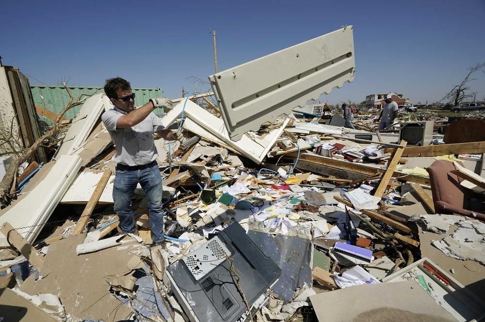 Charlie Weissinger, tosses away the paneling from one of the desks in his father's demolished law office in Rolling Fork, Miss.