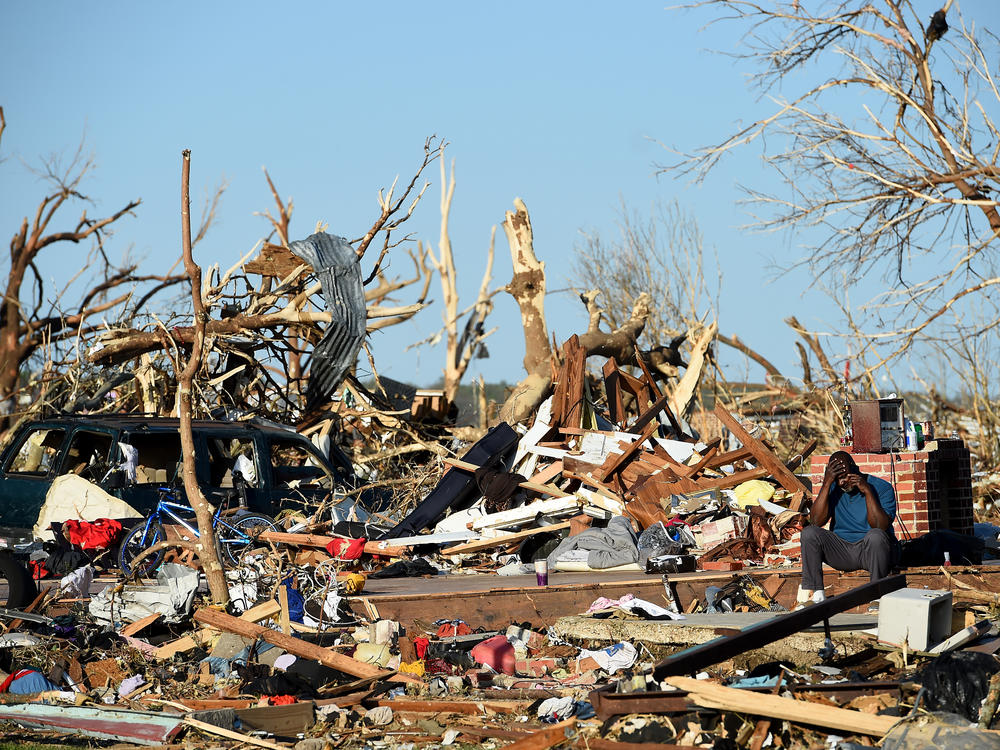 A man sits among the wreckage caused by a series of powerful storms and at least one tornado on March 25, 2023 in Rolling Fork, Mississippi.