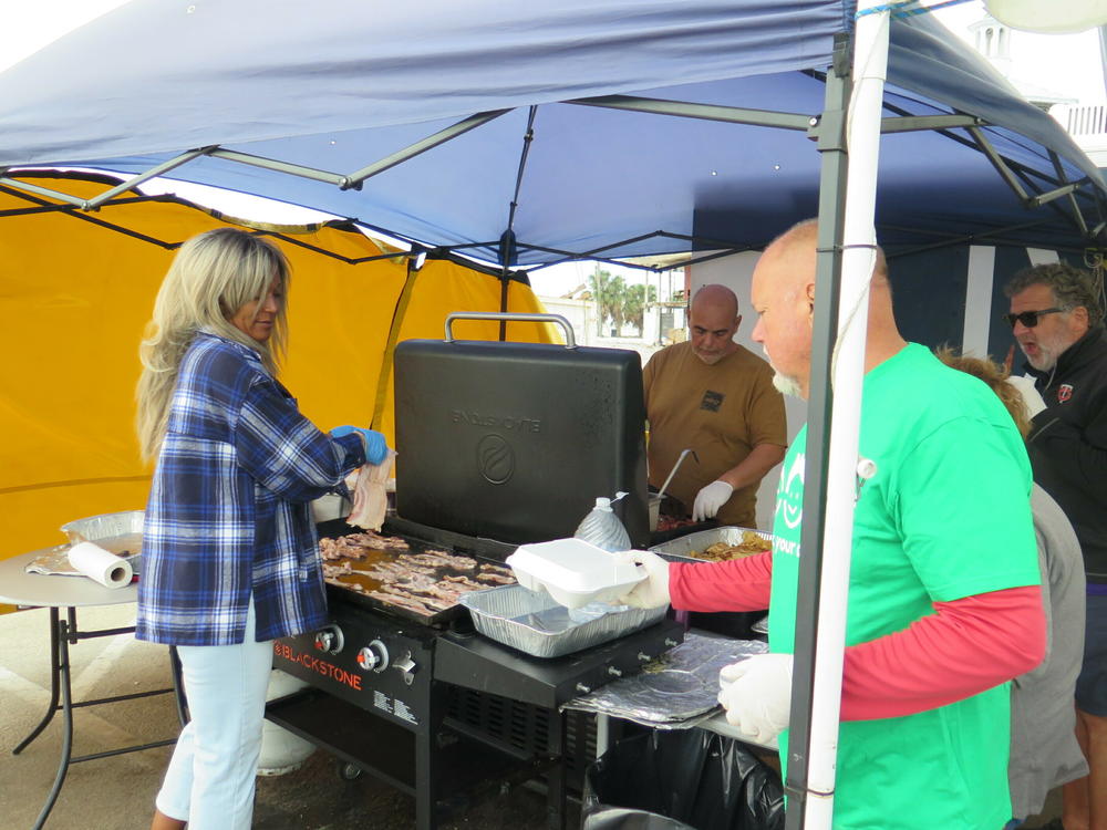 Doug Miller grills up free food to give to weary homeowners and workers at Beach Baptist Church on Fort Myers Beach. Six months after Hurricane Ian walloped Southwest Florida, the recovery is slow and uneven.