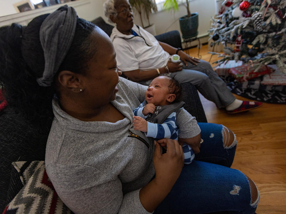 Kennise Nevers holds her son, AJ, in her arms at home. Nevers' mother, Nancy Josey, looks on.