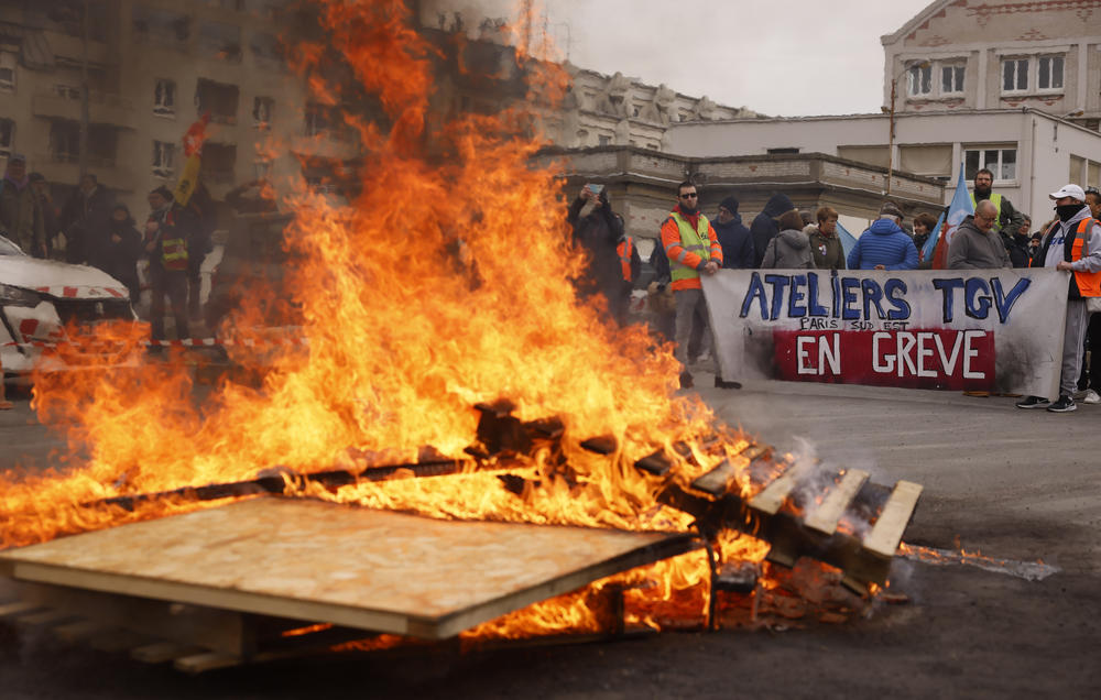 Striking railway workers demonstrate near burning palettes at the Gare de Lyon train station on Tuesday in Paris.