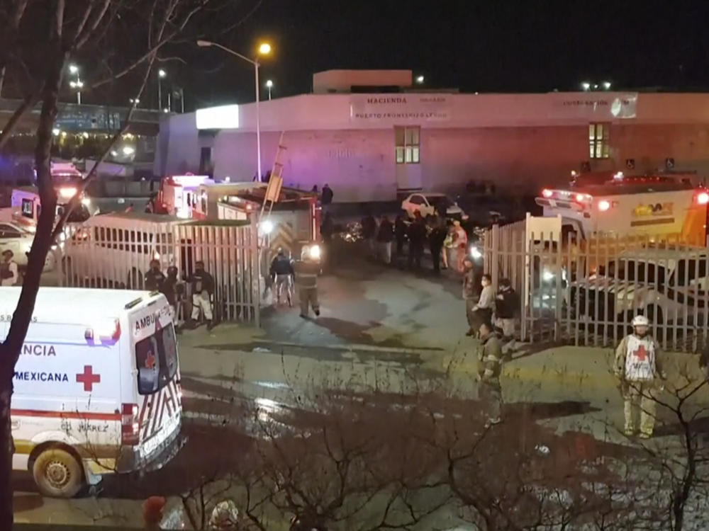 An image taken from a video shows ambulances and rescue team staffers outside an immigration center in Ciudad Juarez, Mexico, on Tuesday.