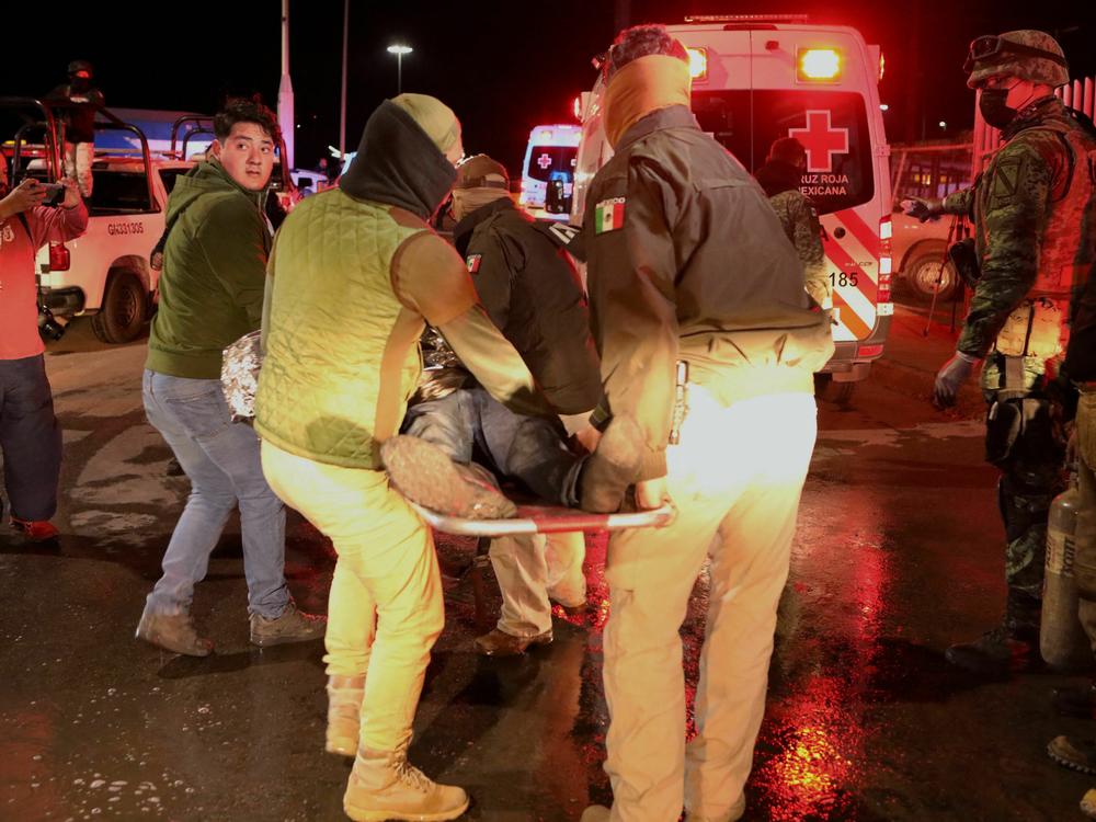 Police officers carry an injured migrant following the fire in Ciudad Juarez, Mexico on Monday.