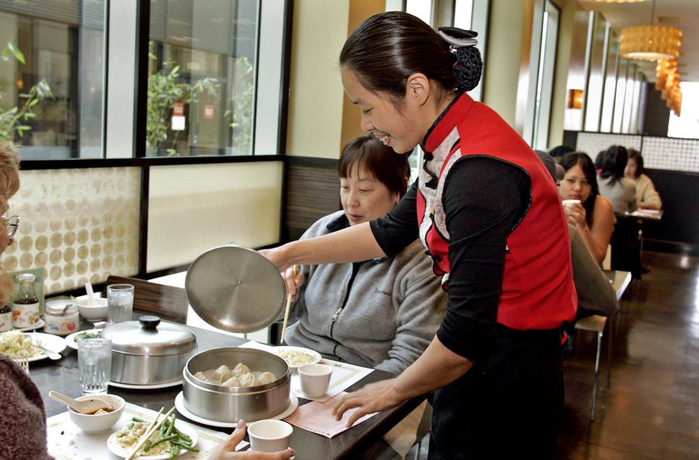 At the Din Tai Fung Dumpling House in Arcadia, California, supervisor and server Cindy Cheng delivers dumplings to a table at lunchtime.