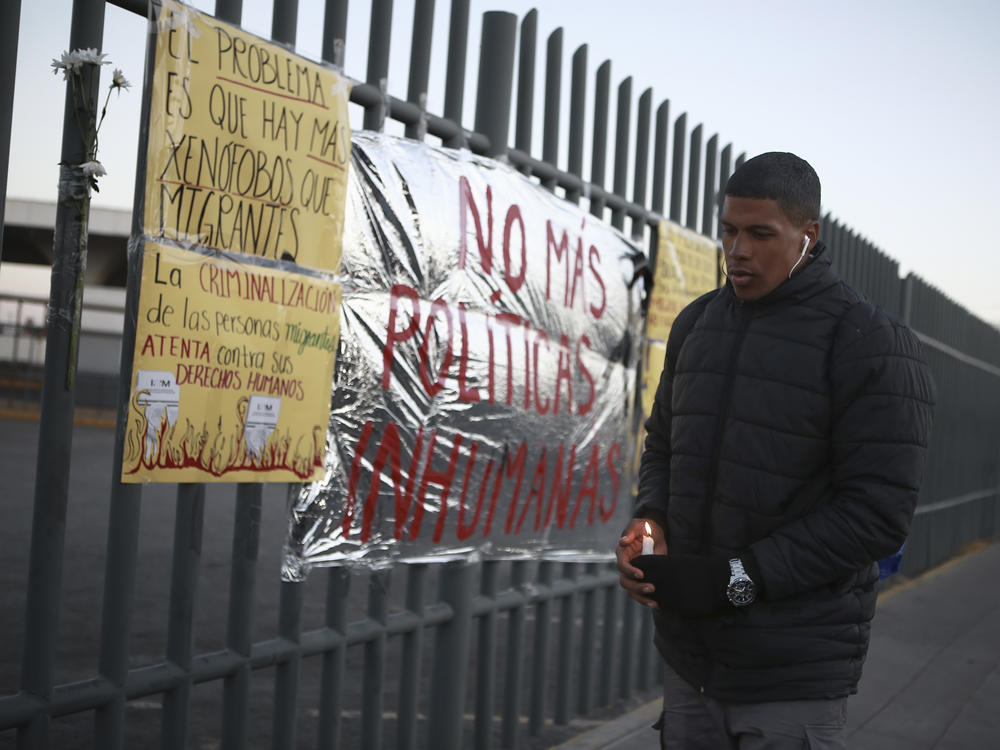 A man holds a candle during a vigil on Tuesday for the victims of a fire at an immigration detention center that killed dozens, in Ciudad Juarez, Mexico. Video footage from inside the facility appears to show officials walking away from men trapped inside a cell as flames roared around them.