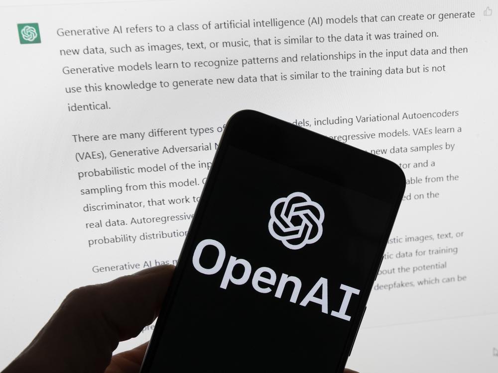 The OpenAI logo is seen on a mobile phone in front of a computer screen displaying output from ChatGPT on March 21, in Boston. A group of prominent computer scientists and other tech industry notables are calling for a 6-month pause to consider the risks of powerful artificial intelligence technology.