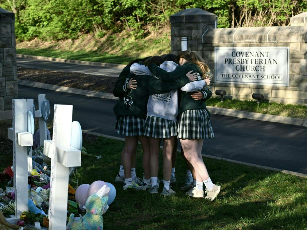 Girls embrace in front of a makeshift memorial for the shooting victims at the Covenant School building on Wednesday.