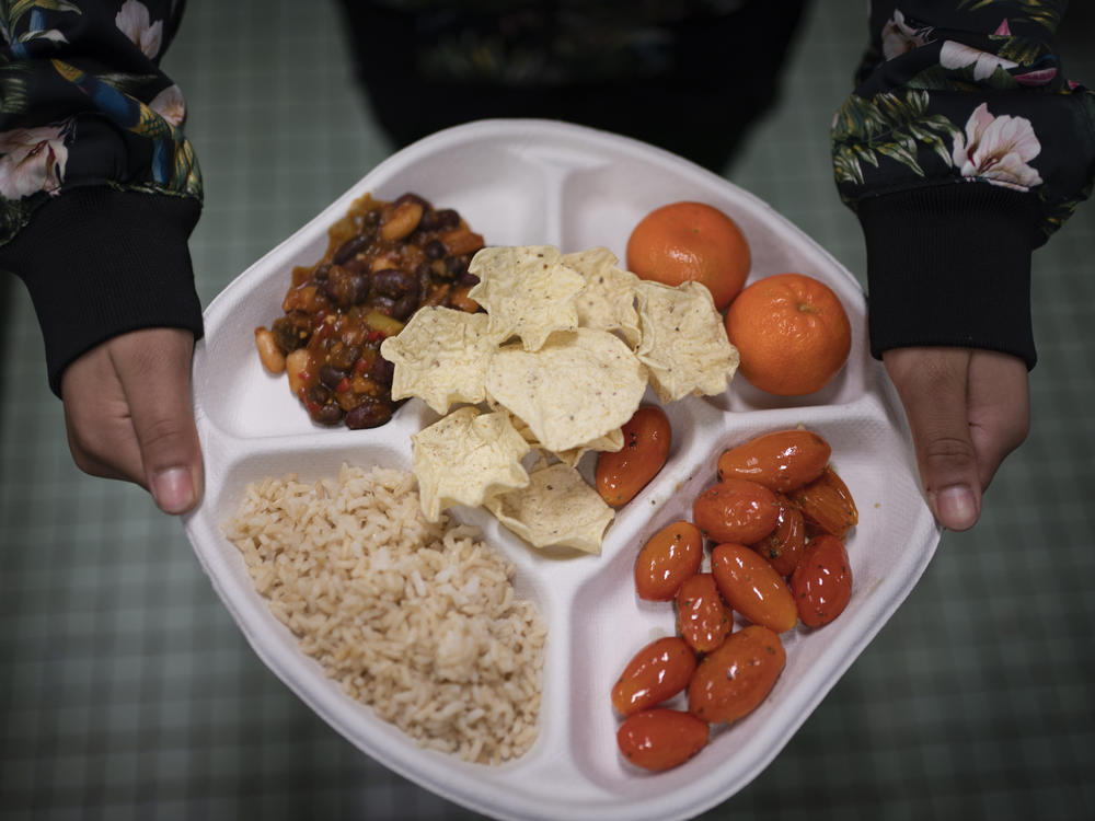 A student carries her plate which consists of three bean chili, rice, mandarins and cherry tomatoes and baked chips during her lunch break at a local public school, Friday, Feb. 10, 2023.