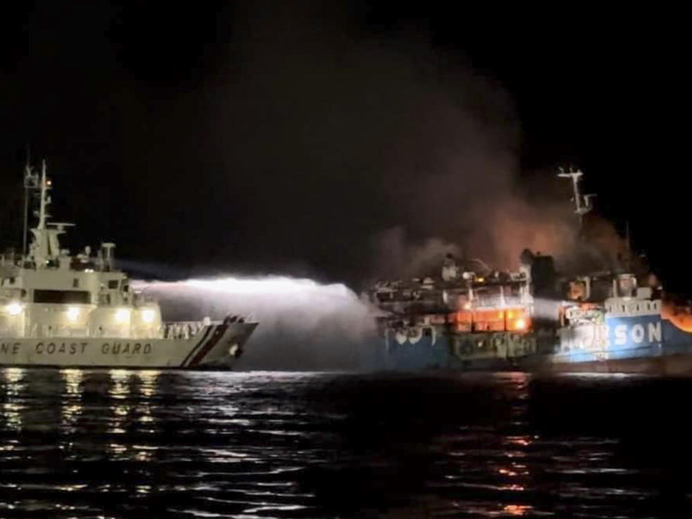 In this photo provided by the Philippine Coast Guard, a Philippine Coast Guard ship trains its hose as it tries to extinguish fire on the MV Lady Mary Joy at Basilan, southern Philippines early Thursday March 30, 2023.