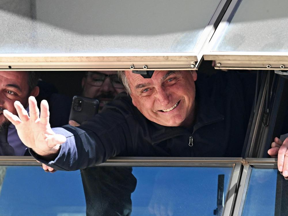 Former Brazilian President Jair Bolsonaro greets supporters from a window at the Liberal Party headquarters in Brasília on Thursday after arriving back in Brazil on a commercial flight from Orlando, Fla.
