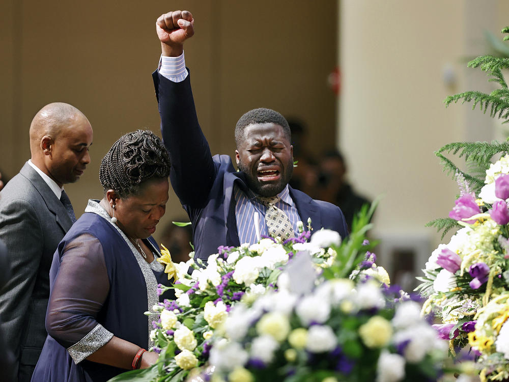 Caroline Ouko, center, and Leon Ochieng, right, the mother and older brother of Irvo Otieno, stand with his casket during his funeral on Wednesday.