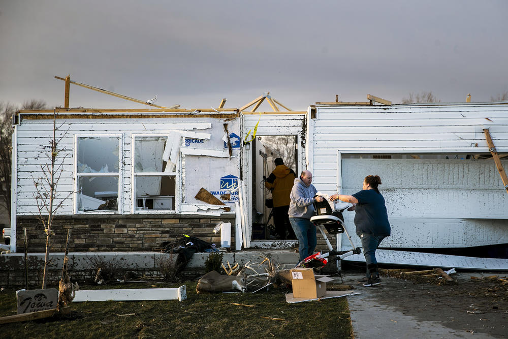 Family and friends help remove personal items from a storm-damaged home after a tornado warning in Johnson County, Iowa, on Friday.