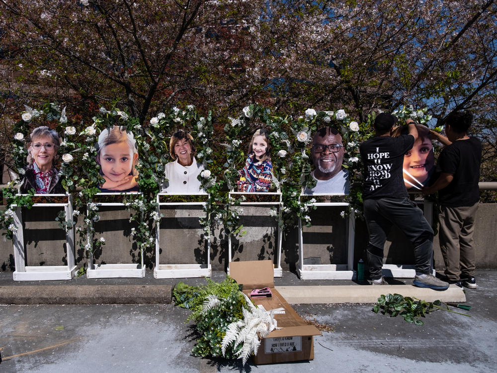 Pictures of the victims killed in a mass shooting on Monday at the Covenant School in Nashville, Tenn., are fixed to a memorial by Noah Reich (left) and David Maldonado, from the nonprofit Classroom of Compassion, near the school on Wednesday.