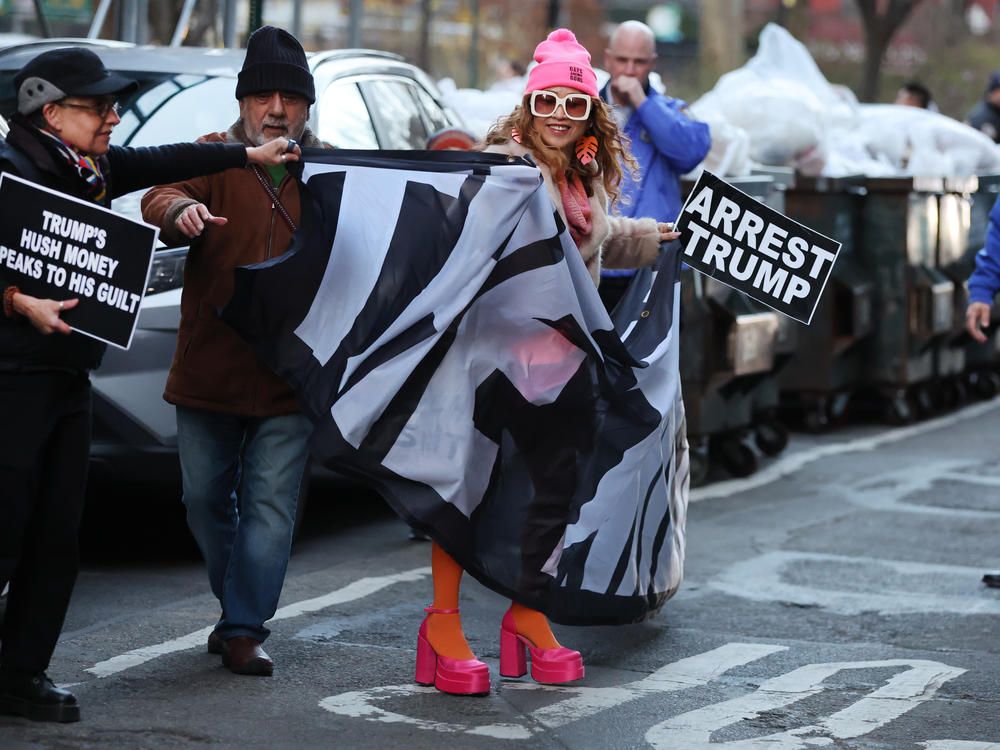 A small group of protesters gathers outside of a Manhattan courthouse after news broke that former President Donald Trump has been indicted by a grand jury on Thursday in New York City, with one pictured carrying a sign that says 