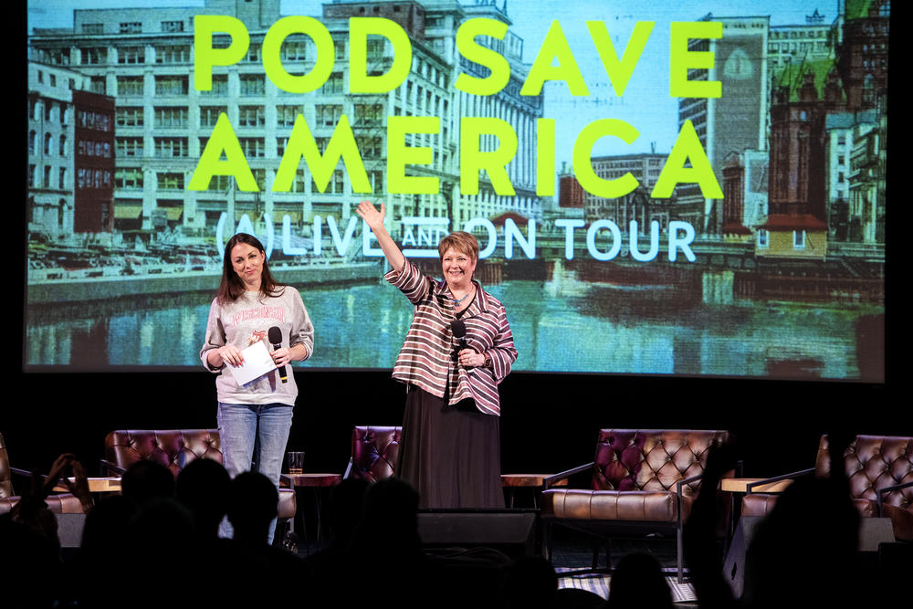 Judge Janet Protasiewicz, center, waves to the audience during a <em>Pod Save America</em> live podcast event March 18 at the Barrymore Theatre in Madison, Wis.