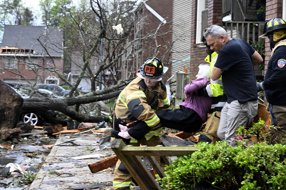 Firefighters carry a woman out of her condo after her complex was damaged by a tornado on Friday in Little Rock, Ark.