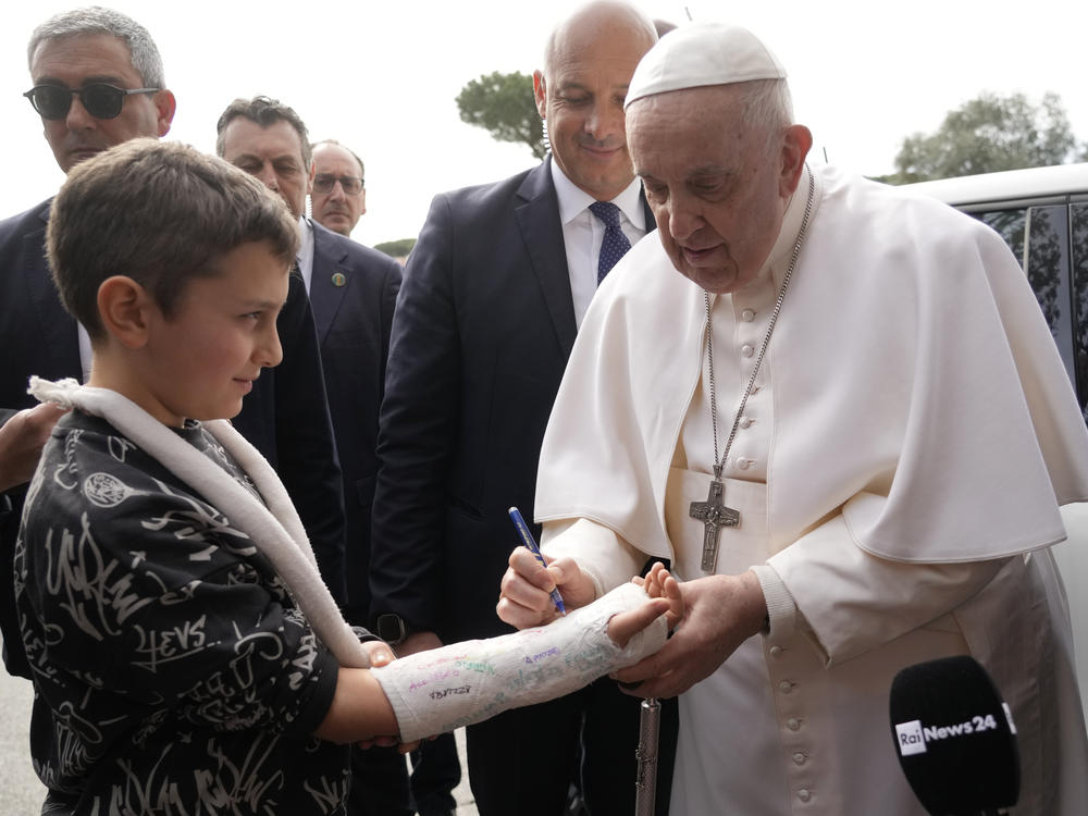 Pope Francis autographs the plaster cast of a child as he leaves the Agostino Gemelli University Hospital in Rome on Saturday.
