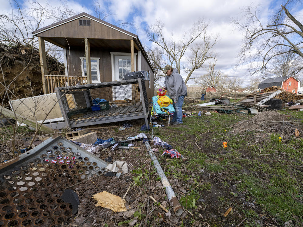 Misty Grimes searches through debris scattered throughout her yard left from a late-night tornado in Sullivan, Ind. Grimes and her husband, Matt, were home as the storm hit, and found shelter inside their home. Neither were injured.