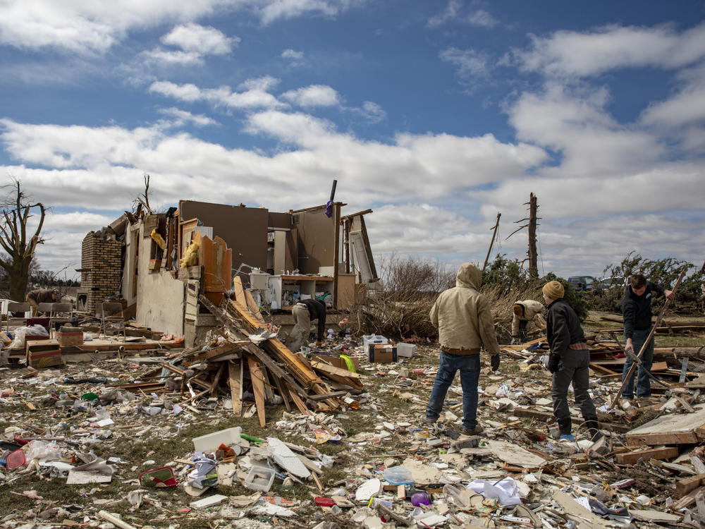 Family and neighbors look through debris on Ed Whestine's farm southwest of Wellman, Iowa on Saturday. Storms that dropped possibly dozens of tornadoes killed multiple people in small towns and big cities across the South and Midwest.