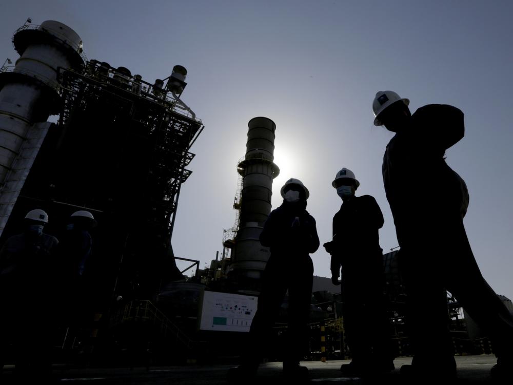 Saudi Aramco engineers walk in front of a gas turbine generator at Khurais oil field during a tour for journalists, about 93 miles east-northeast of Riyadh, Saudi Arabia, on June 28, 2021.