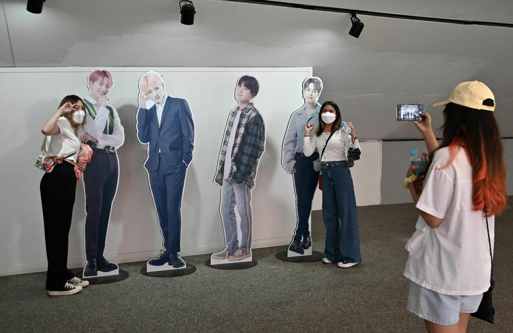 Visitors pose with cardboard cutouts of K-pop group BTS members at a tourist information center in Seoul on June 15, 2022.