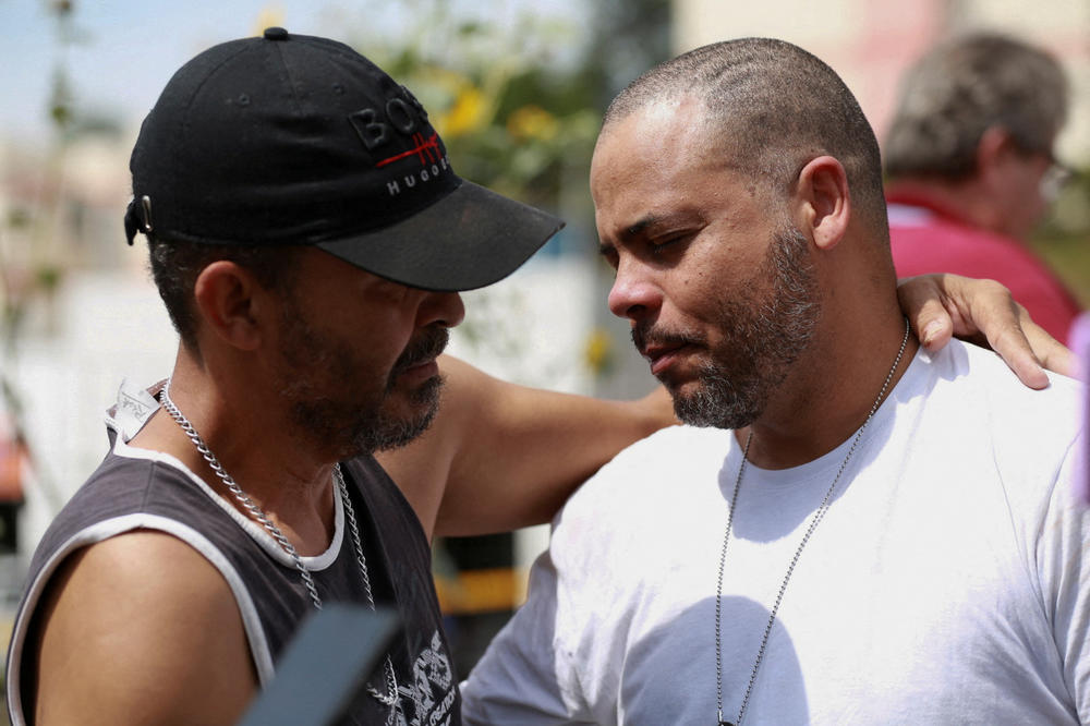 Men react outside a daycare center in Blumenau, Brazil, after a 25-year-old man armed with an axe attacked children, killing several and injuring others. The attack took place on April 5.