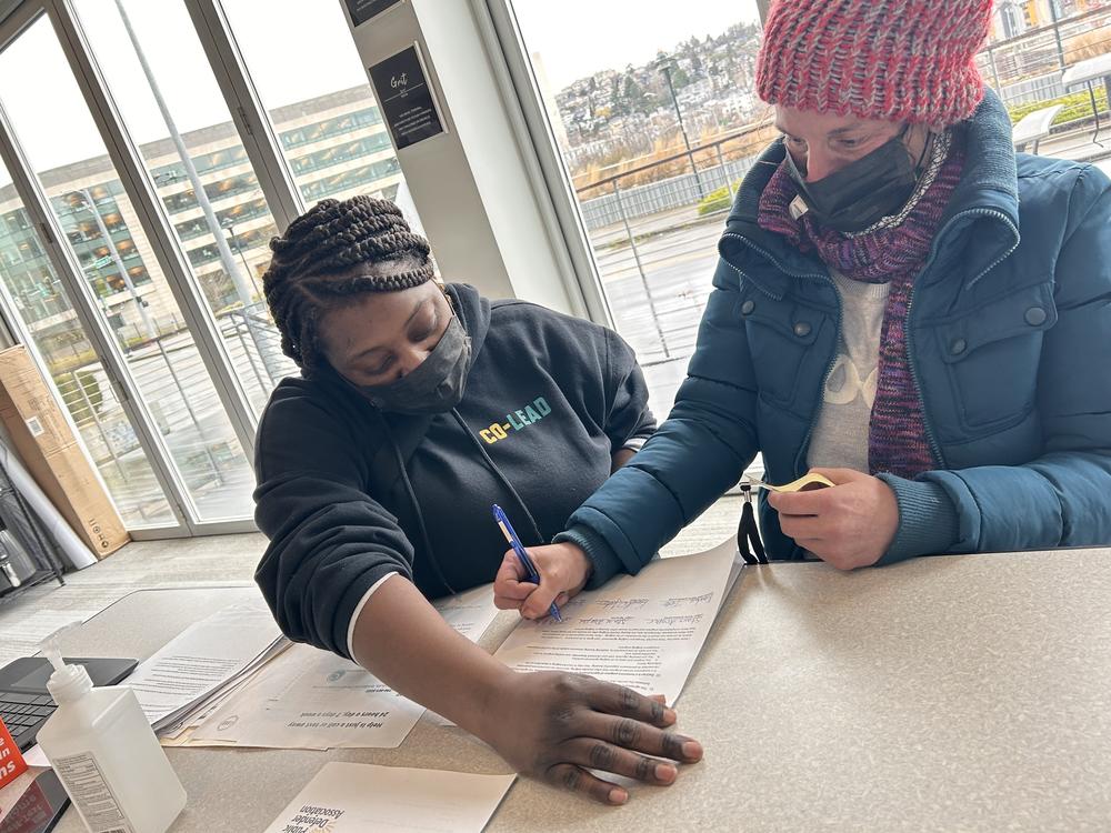 JustCARE outreach worker Kendra Tate (left) helps Starr Draper complete paperwork necessary for her to move from a homeless encampment into a temporary home.