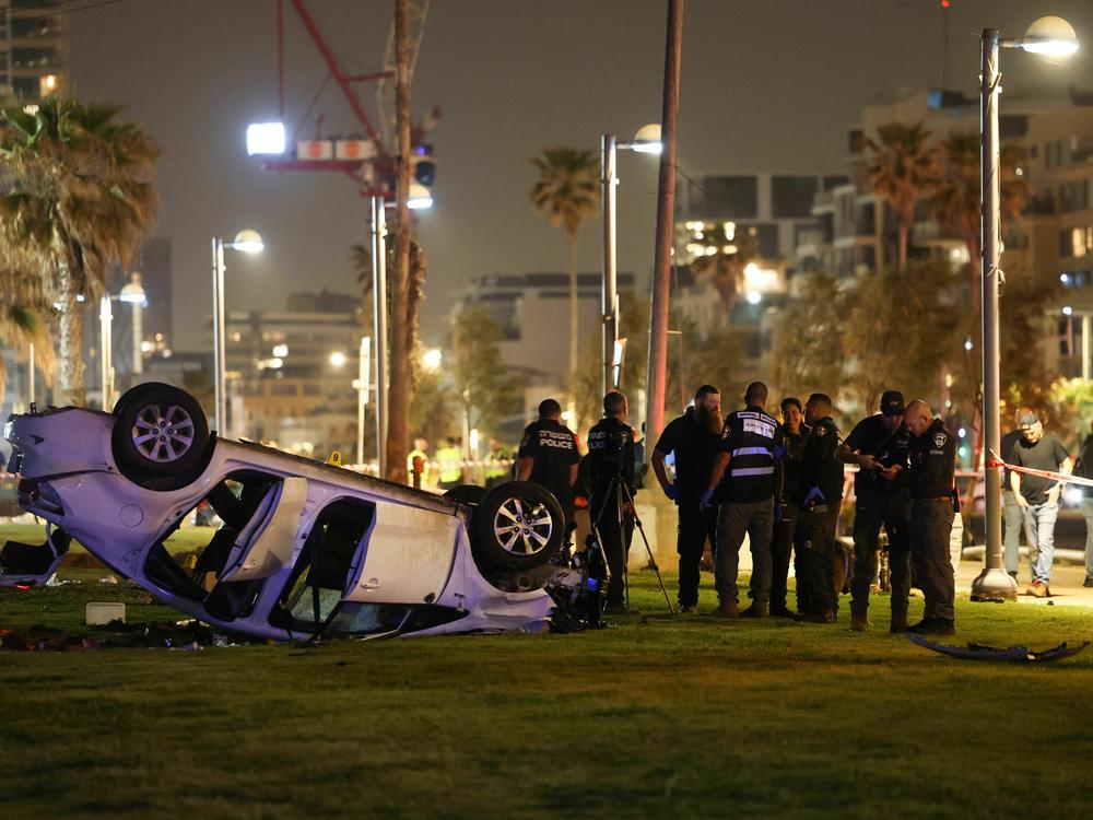Israeli police gather next to an overturned car at the site of an attack Friday in Tel Aviv in which an Italian tourist was killed and several other people were injured.