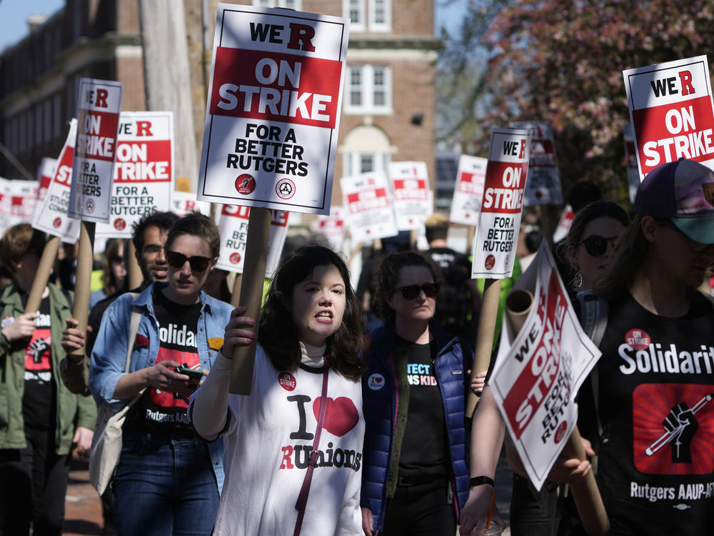 Strikers march in front of Rutgers University buildings in New Brunswick, N.J., on Monday, April 10, 2023.