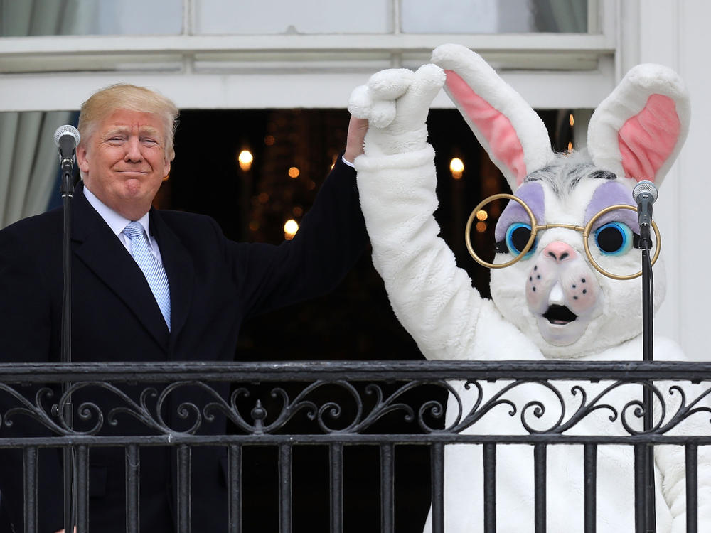 Former President Donald Trump (L) lifts the hand of a person in an Easter Bunny costume on the Truman Balcony during the 140th annual Easter Egg Roll on the South Lawn of the White House April 2, 2018 in Washington, D.C.