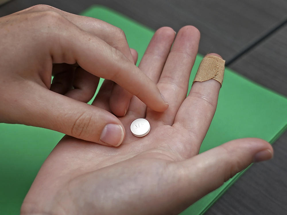 A patient prepares to take the first of two pills for a medication abortion during a visit to a clinic in Kansas City, Kan., on Wednesday, Oct. 12, 2022.