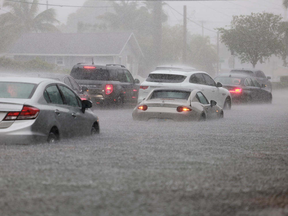 Cars are parked in a flooded street on Wednesday in Dania Beach, Florida.