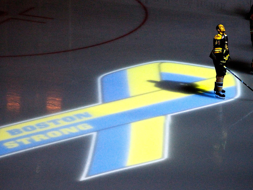 A player for the Boston Bruins stands near a projection of the Boston Marathon Memorial Ribbon seen on the ice during a pre game ceremony on April 17, 2013.