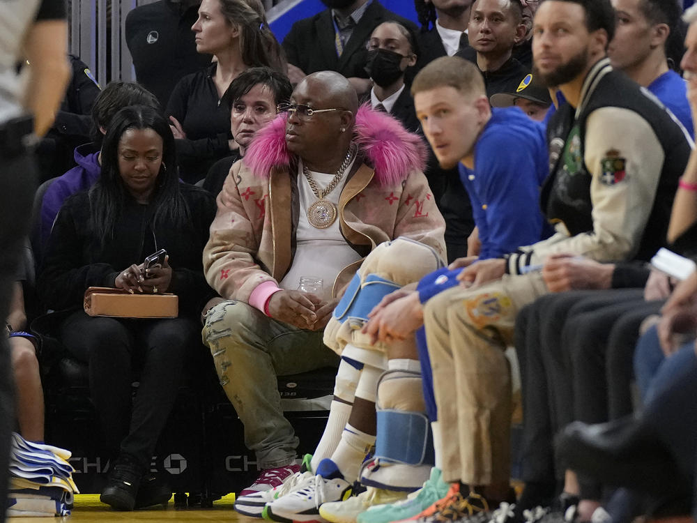 E-40, middle, watches during an NBA basketball game between the Golden State Warriors and the Portland Trail Blazers in San Francisco, Dec. 30, 2022. The Sacramento Kings are investigating allegations from the rapper E-40 that 