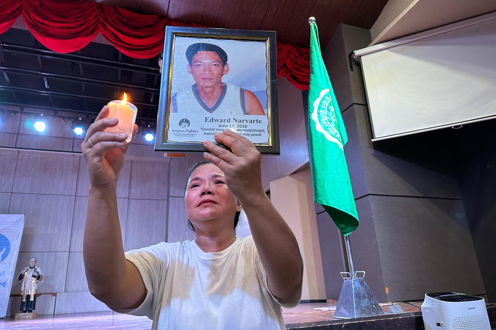 Amelia Santos, 55, holds up a portrait of her late husband, Edward Navarte, during a recent performance. Santos says her husband was targeted in a 2016 extrajudicial killing by police as part of the Philippines' war on drugs.