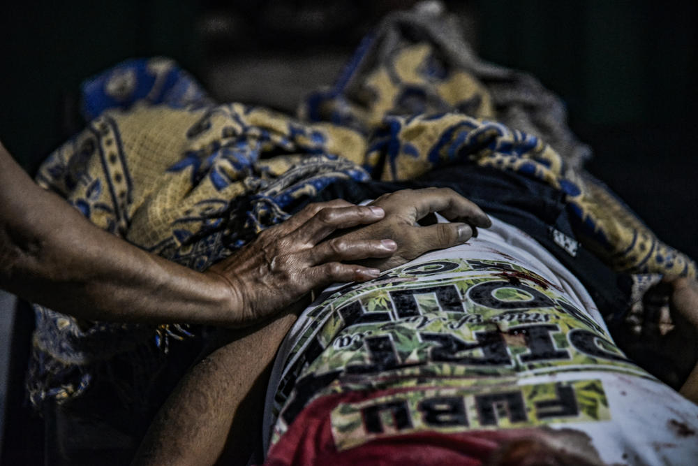 A relative holds the hand of Jonathan Sevilla, who was shot dead by unknown attackers, at a morgue in Malabon, Metro Manila, Philippines, March 23, 2018.