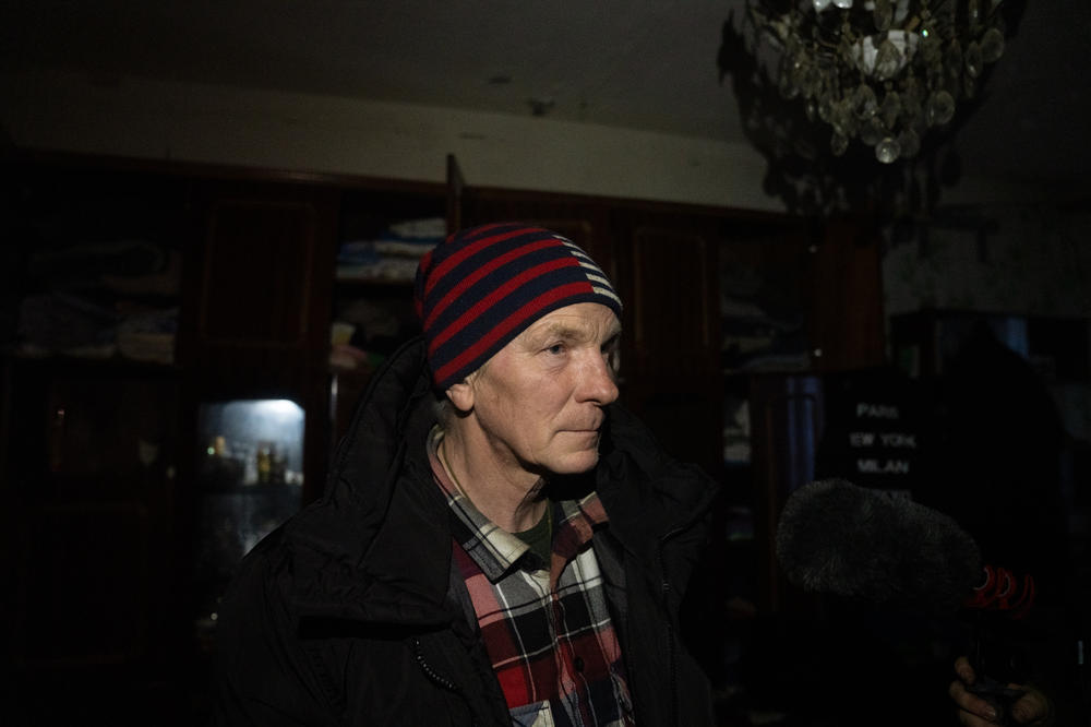 Ihor Dudnik stands in the dark inside the building where he lived with his wife prior to the war. They moved to temporary housing to escape the violence but after his wife died of heart failure in December, he returned, alone, to his crushed home.